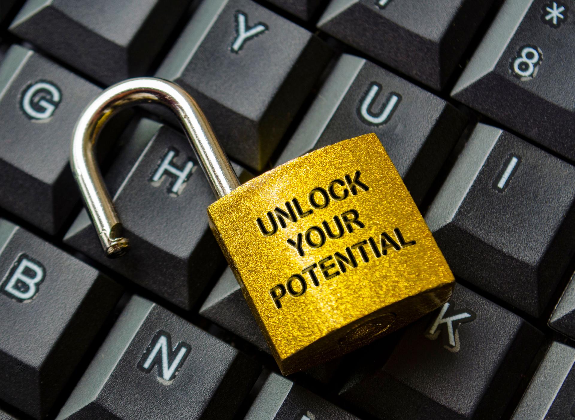 Unlock Your Potential text engraved on golden padlock with keyboard background. Motivational and Inspirational concept